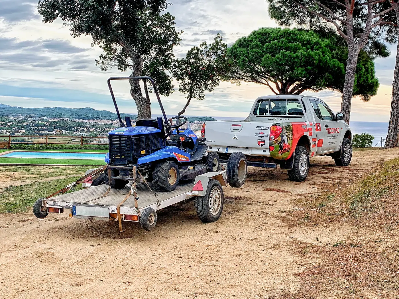 Vehicles de Tecomac amb un tractor tallagespa i remolc a l'Empordà
